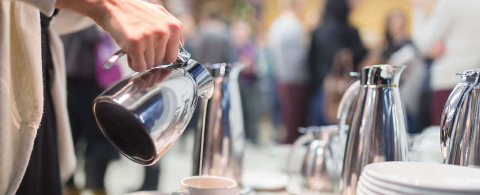 En person i en möteslokal häller upp kaffe i en kopp