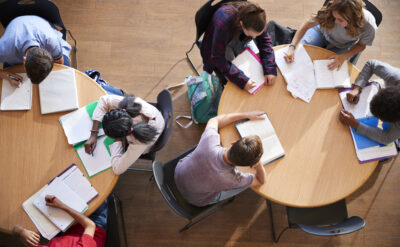Elever sitter vid runda bord och studerar.