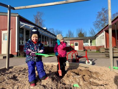 Två barn leker i sandlådan framför Kråkbackens förskola.