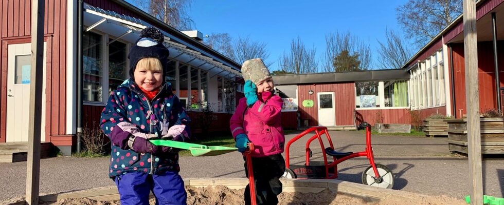 Två barn leker i sandlådan framför Kråkbackens förskola.