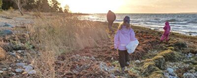 barn som går på en stenig strand med en plastpåse