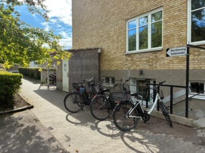 Parkerade cyklar och till vänster om dem hjälpmedelsförrådet utanför entrén vid Ekbacka.